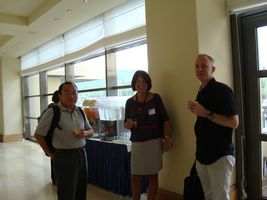Bozenna and 2 male attendees with refreshments smiling at camera